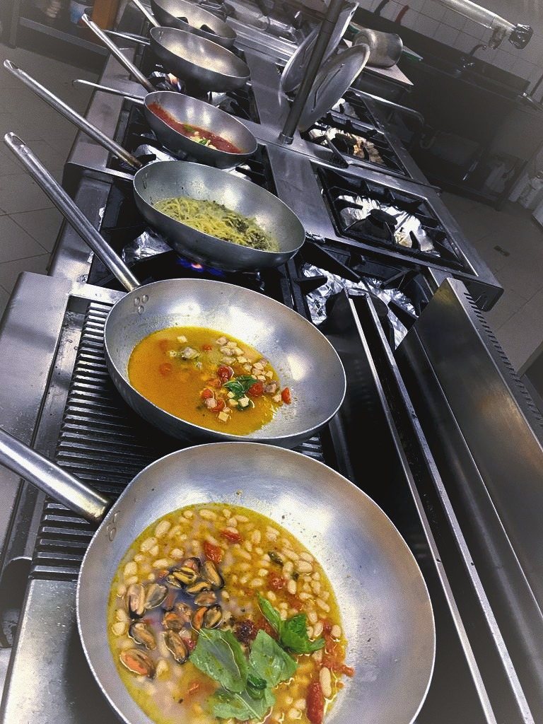 La cucina di Don Raffaele: padelle sul fuoco durante il servizio