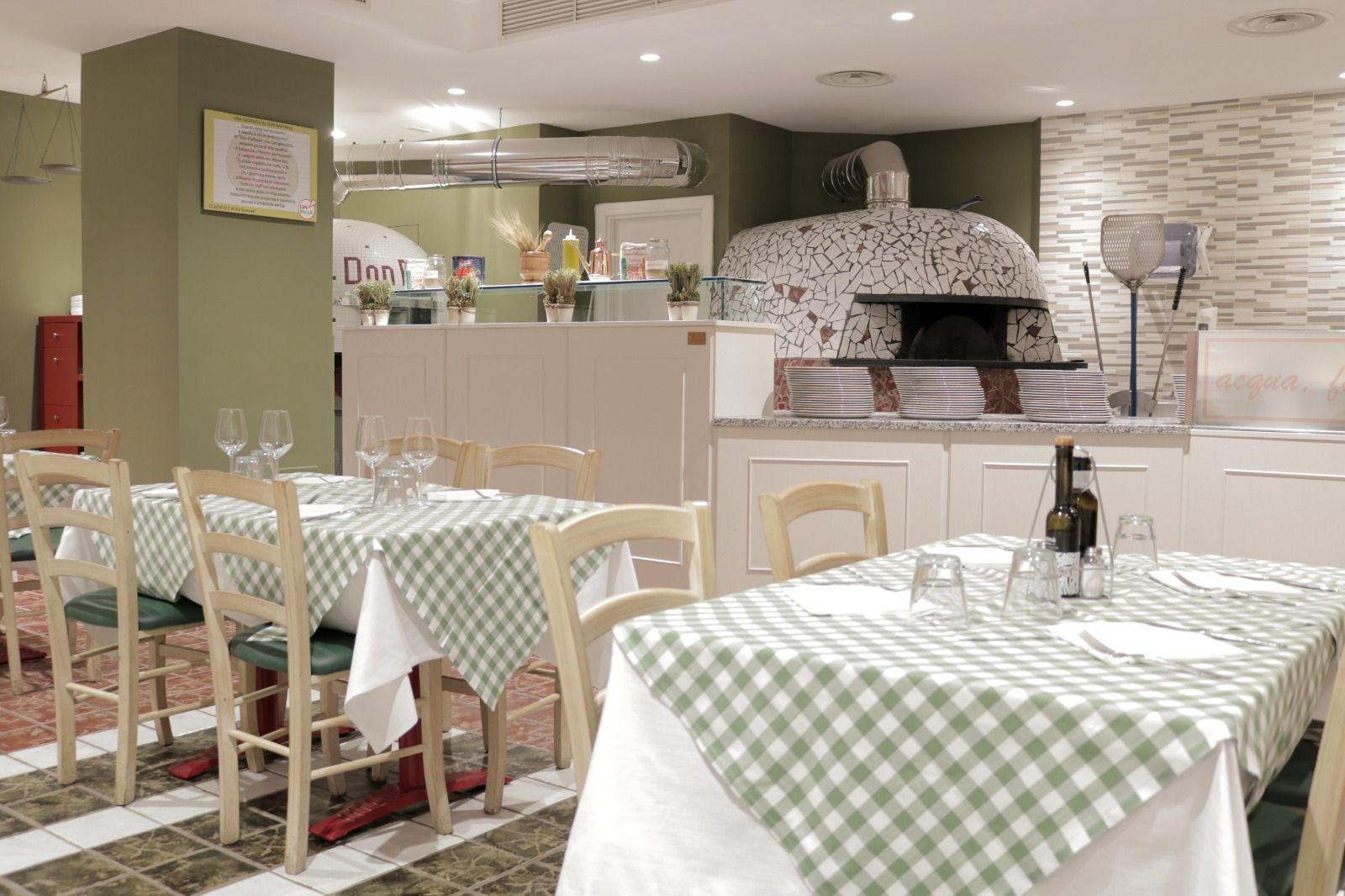 Il forno a legna al centro della sala di Don Raffaele con i tavoli a quadretti verdi