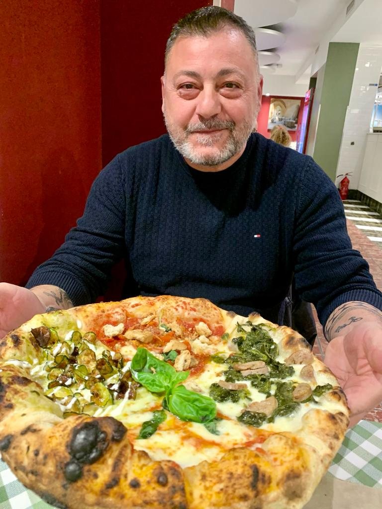 Il pizzaiolo di Don Raffaele presenta una pizza appena sfornata